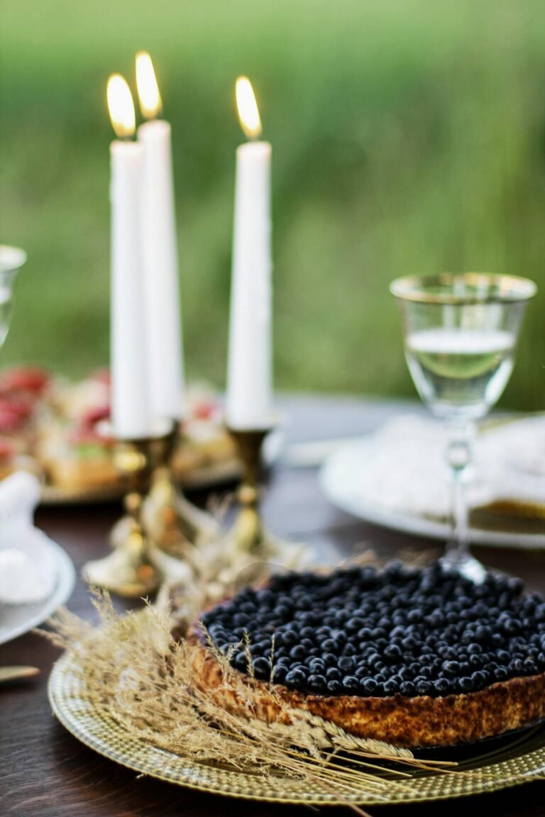 A blueberry tart on a festive table with candles and drinks, perfect for celebrations.