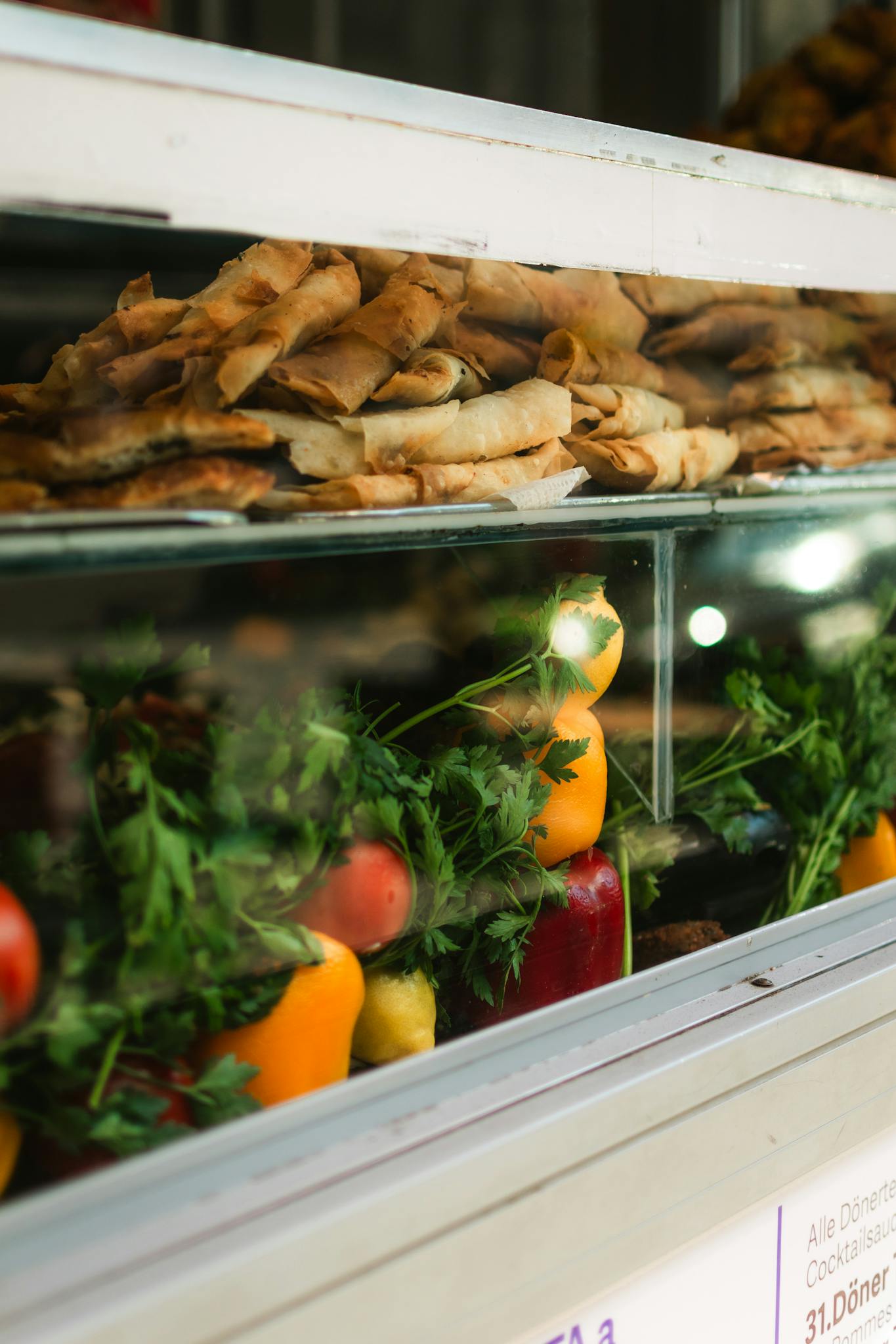 A vibrant display of fresh vegetables and pastries in a street food stall window.