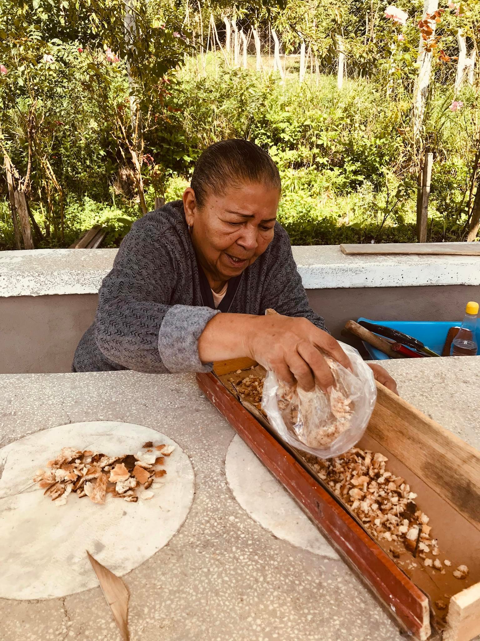 Woman preparing ingredients outdoors, showcasing traditional food preparation method.